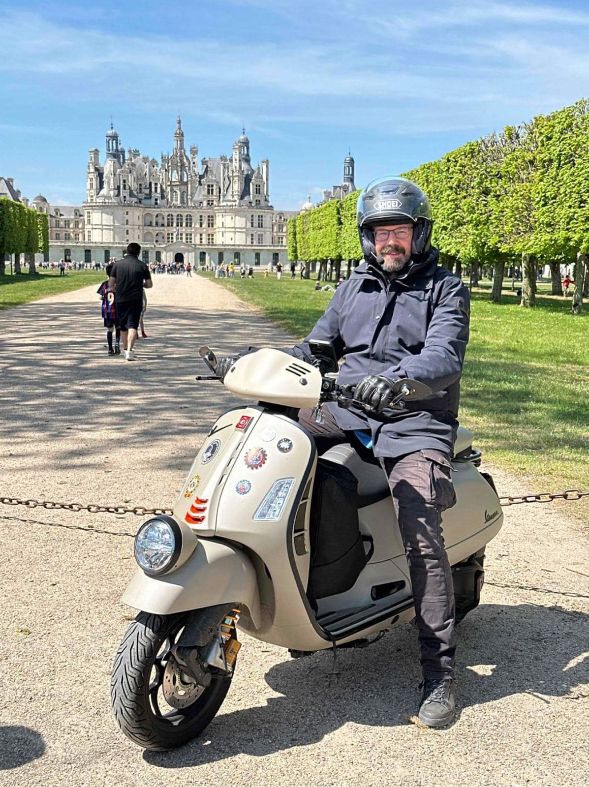 Marc Griffone riding a vespa in front of a castle